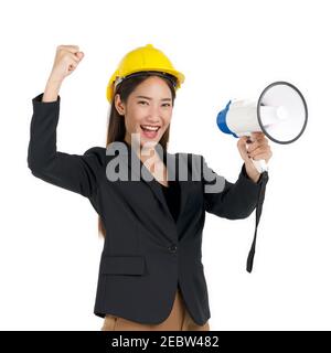 Une femme d'affaires portant un casque de construction jaune cria à un mégaphone. Portrait sur fond blanc avec lumière studio. Banque D'Images