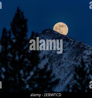 États-Unis, Idaho, Sun Valley, pleine lune qui s'élève au-dessus des montagnes Boulder en hiver Banque D'Images