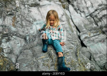 Un petit préchooler escalade sur quelques rochers dans le automne Banque D'Images