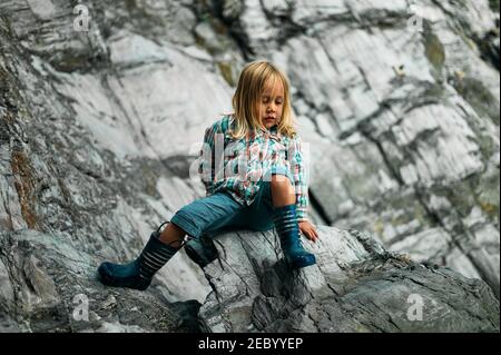 Un petit préchooler escalade sur quelques rochers dans le automne Banque D'Images