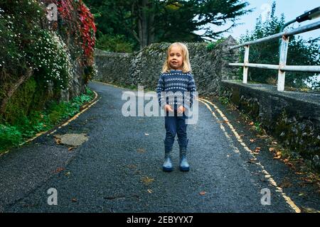 Un petit préchooler est debout dans la route à l'extérieur l'automne Banque D'Images