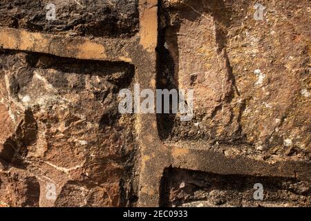 détail de la pointe jaune pâle relevée utilisée entre la construction en pierre de construction et de détail des striations dans le rocher Banque D'Images