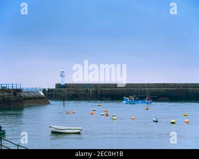 Mevagissey, Cornwall. Un bateau de pêche commercial quitte l'avant-port au crépuscule. Banque D'Images