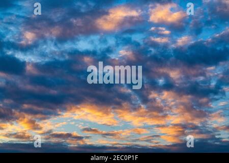 Des nuages étonnants dans le ciel bleu, illuminés par des rayons de soleil au coucher du soleil pour changer le temps. Mise au point douce, flou de mouvement coloré résumé météorologie arrière-plan. Banque D'Images