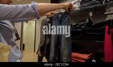 Strasbourg, France - 29 juillet 2017 : une femme qui fait ses courses à l'intérieur d'un magasin pour une nouvelle paire de jeans - mesurer dans l'air le luxueux vêtement en denim bleu biologique Banque D'Images