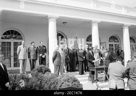 Cérémonie d'assermentation, général Maxwell Taylor, Président, JCS, 12 h 00. Le président John F. Kennedy (au centre à droite, à micros) prononce des remarques lors de la cérémonie d'assermentation du général Maxwell D. Taylor en tant que président des chefs d'état-major interarmées (JCS); le général Taylor et le procureur général, Robert F. Kennedy, se tiennent à droite du président Kennedy. En regardant les marches de la Colonnade de l'aile Ouest, en commençant à l'extrême gauche (de gauche à droite): Aide militaire au président, le général Chester V. Clifton; aide aérienne au président, le général de brigade Godfrey T. McHugh; aide navale au président, le capitaine Banque D'Images