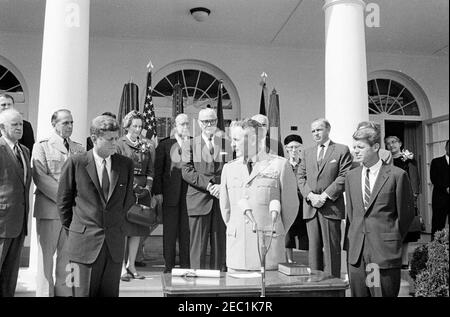 Cérémonie d'assermentation, général Maxwell Taylor, Président, JCS, 12 h 00. Le général Maxwell D. Taylor (au centre à droite, à micros) prononce des remarques lors de sa cérémonie d'assermentation en tant que président des chefs d'état-major interarmées (JCS); le président John F. Kennedy (à gauche) et le procureur général Robert F. Kennedy, se tiennent de part et d'autre du général Taylor. En regardant depuis les marches de la Colonnade de l'aile ouest, en commençant tout à l'arrière (de gauche à droite): L'aide navale au Président, le Capitaine Tazewell T. Shepard, Jr. (Partiellement caché); le général Omar Bradley; le Président sortant du JCS, le général Lyman L. Lemnitzer; Lydia Banque D'Images