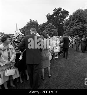 Visite des participants à la Conférence de campagne 1962 pour les femmes démocratiques, 9 h 35. Le président John F. Kennedy, la première dame Jacqueline Kennedy et la vice-présidente Lyndon B. Johnson saluent les participants à la Conférence de campagne 1962 pour les femmes démocratiques. Les photographes non identifiés se trouvent tout à droite ; le Washington Monument est visible en arrière-plan. South Lawn, Maison Blanche, Washington, D.C. Banque D'Images