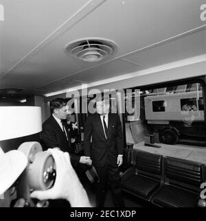 Cérémonies de dédicace, aéroport international de Dulles, 11:12. Le président John F. Kennedy (centre, chapeau de compagnie) traverse l'un des salons mobiles de l'aéroport international de Dulles, au cours des cérémonies de dédicace de l'aéroport, nommé d'après le regretté secrétaire d'État John Foster Dulles. L'administrateur de l'Agence fédérale de l'aviation (FAA), Najeeb Halaby, marche à gauche; Aline B. Saarinen (veuve de l'architecte de l'aéroport, Eero Saarinen) suit. Chantilly, Virginie. Banque D'Images