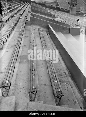 Installation d'une boîte présidentielle au stade municipal de Philadelphie. Vue sur les stands du Municipal Stadium de Philadelphie, Pennsylvanie, lors de l'installation d'une boîte présidentielle en préparation de la participation du Président John F. Kennedyu0027s au match de football de l'Armée de terre et de la Marine de 1962. L'agent du service secret de la Maison Blanche, Stu Stout (portant un chapeau), et un homme non identifié se tiennent à droite en arrière-plan. [La ligne verticale le long du côté droit de l'image est originale au négatif.] Banque D'Images