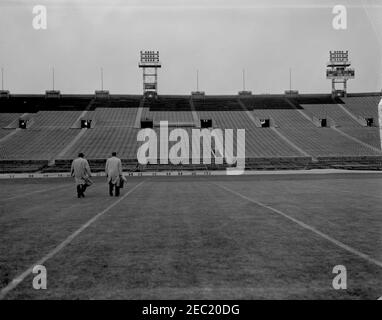 Installation d'une boîte présidentielle au stade municipal de Philadelphie. Vue du stade municipal de Philadelphie, Pennsylvanie, lors de l'installation d'une boîte présidentielle en préparation à la participation du Président John F. Kennedyu0027s au match de football de l'Armée de terre et de la Marine 1962. Deux personnes non identifiées (toutes deux à gauche) traversent le champ. [Le défaut sur le côté droit de l'image est original sur le négatif.] Banque D'Images