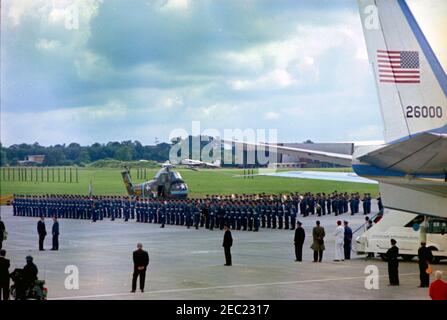 Voyage en Europe: Angleterre, Gatwick: Le Président Kennedy arrive à l'aéroport de Gatwick, accueilli par le Premier ministre britannique Harold Macmillan, à 5:30. Le président John F. Kennedy (en marchant au centre) examine les troupes britanniques après son arrivée à bord de l'Air Force One à l'aéroport de Gatwick à West Sussex, en Angleterre. Un hélicoptère de l'armée des États-Unis se trouve sur le tarmac. Banque D'Images