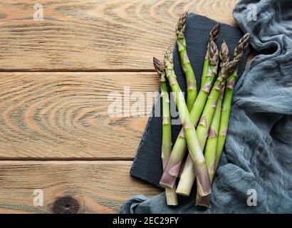 Asperges vertes fraîches sur une ancienne table en bois. Pose à plat Banque D'Images