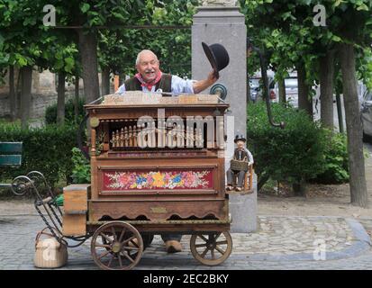 Artiste de rue à Bruges, Belgique. Un homme âgé se produit pour les touristes avec un orgue de tonneau à l'ancienne. Banque D'Images