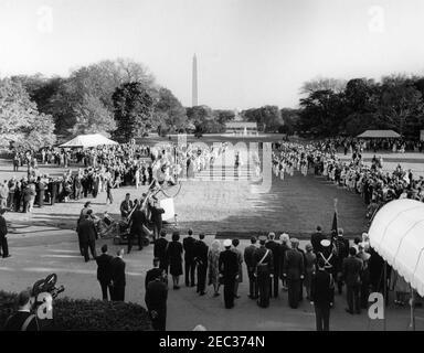 Le Président Kennedy salue les récipiendaires de la Médaille d'honneur du Congrès, réception militaire annuelle, 6 h 03. Vue de la pelouse sud de la Maison Blanche, comme l'Old Guard Fife and Drum corps, 1er Bataillon, 3e Régiment d'infanterie, se produit lors d'une réception militaire en l'honneur des récipiendaires de la Médaille d'honneur du Congrès. Le président John F. Kennedy et d'autres regardent les débats du Portico du Sud (à droite, au premier plan). Le Washington Monument et le Jefferson Memorial sont visibles au loin. Washington, D.C. Banque D'Images