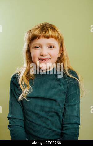 portrait d'une fille blonde souriante sur fond vert Banque D'Images