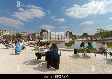 Jardin des Tuileries, Paris. Les touristes et les Parisiens se détendent sous le soleil de printemps autour d'une des piscines dans les jardins formels. Banque D'Images