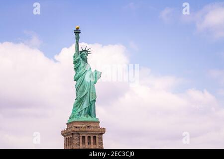 Vue sur la Statue de la liberté à New York depuis le côté avant gauche avec le ciel bleu nuageux dedans l'arrière-plan Banque D'Images