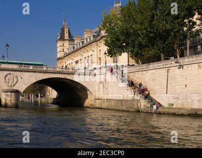 Marches menant à la Seine depuis le Palais de Justice, Paris. Les touristes et les Parisiens profitent du soleil d'automne sur la rivière. Banque D'Images