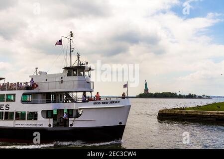 Miss New Jersey croisière ferry bateau transportant des touristes à l'approche de la port avec la Statue de la liberté en arrière-plan Banque D'Images