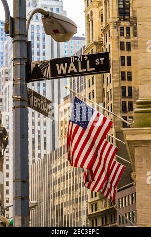 Panneau de Wall Street à New York sur une rue Lampe avec trois drapeaux américains et des bâtiments en arrière-plan Banque D'Images