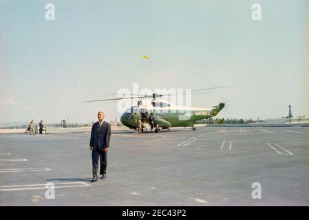 Voyage aux États de l'Ouest : Los Angeles, Californie, arrivée à l'hôtel Beverly Hilton pour un dîner de collecte de fonds, 3:40. Le président John F. Kennedy (en arrière-plan, au bas des escaliers de l'hélicoptère) quitte un hélicoptère du corps des Marines des États-Unis à son arrivée à l'héliport sur le toit de l'hôtel Beverly Hilton à Los Angeles, en Californie; l'agent secret de la Maison Blanche, Don Lawton, se trouve au premier plan. Le président Kennedy s'est rendu à Los Angeles pour assister à un dîner de collecte de fonds du Parti démocratique. Banque D'Images