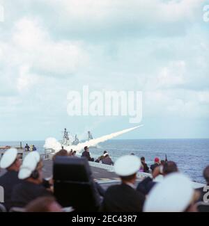 Voyage aux États de l'Ouest : visite de la flotte du Pacifique, le président Kennedy à bord de l'USS Kitty Hawk, 5:00. Le président John F. Kennedy (assis sur la chaise à dossier haut à gauche) et d'autres invités distingués regardent des démonstrations guidées de missiles depuis le pont de vol du porte-avions USS Kitty Hawk (CVA-63), lors d'une visite à la flotte du Pacifique des États-Unis au large de la côte de San Diego, en Californie. Banque D'Images