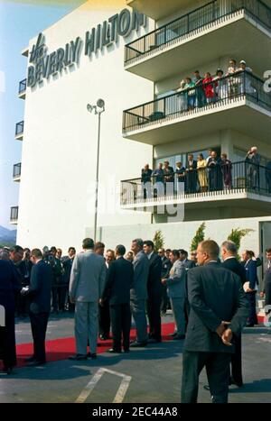 Voyage aux États de l'Ouest : Los Angeles, Californie, arrivée à l'hôtel Beverly Hilton pour un dîner de collecte de fonds, 3:40. Le président John F. Kennedy (en bas à gauche, debout sur un tapis rouge) accueille un groupe de personnes non identifiées, après son arrivée à l'héliport sur le toit de l'hôtel Beverly Hilton à Los Angeles, en Californie. Le gouverneur de Californie, Edmund G. u201cPatu201d Brown, est visible à l'extrême gauche; le président Kennedy s'est rendu à Los Angeles pour assister à un dîner de collecte de fonds du Parti démocratique. Banque D'Images