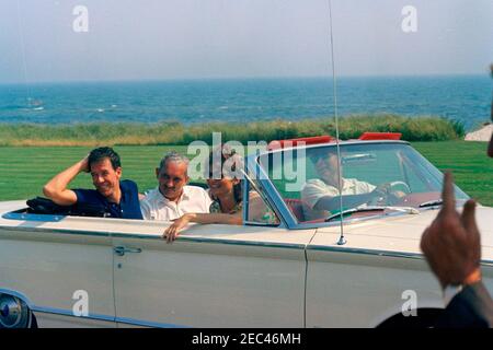 Week-end au port de Hyannis : croisière à bord du Honey Fitz avec famille et amis. Le président John F. Kennedy (au siège de driveru2019s) et la première dame Jacqueline Kennedy (au siège passager) sont assis dans un cabriolet à Hyannis Port, Massachusetts. Assis à l'arrière de la voiture (G-D): L'ami de la famille Kennedy, Charles Spalding; le premier beau-frère Ladyu2019s, le prince Stanislaus Radziwill de Pologne. Banque D'Images