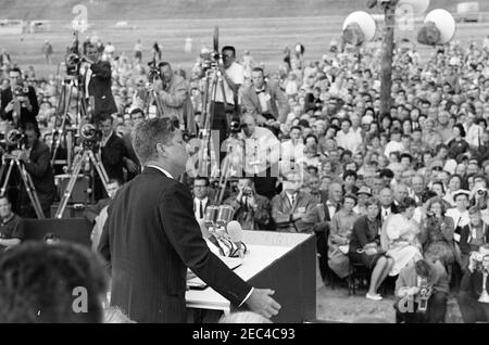 Voyage aux États de l'Ouest : Pierre, Dakota du Sud (barrage d'Oahe), 10:25. Le président John F. Kennedy (au lectern) prononce un discours à l'inauguration du barrage et du réservoir d'Oahe, sur les rives de la rivière Missouri, près de Pierre, Dakota du Sud; les membres de la presse et le public observent. Également photographié (à l'extrême gauche en arrière-plan) : photographe de presse pour United Press Movietone, Thomas J. Craven, Sr. ; électricien du réseau de médias de la Maison Blanche, Cleve Ryan. Banque D'Images