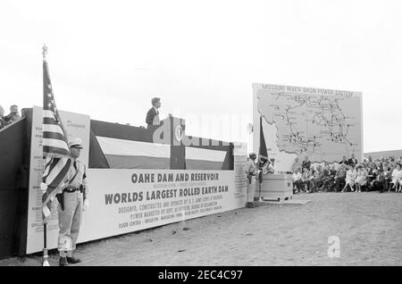 Voyage aux États de l'Ouest : Pierre, Dakota du Sud (barrage d'Oahe), 10:25. Le président John F. Kennedy (au lectern) fait des remarques sur la plateforme Speakersu0027 lors de l'inauguration du barrage et du réservoir d'Oahe, sur les rives de la rivière Missouri, près de Pierre, Dakota du Sud. Les membres de la protection de couleur bordent la plate-forme. Banque D'Images