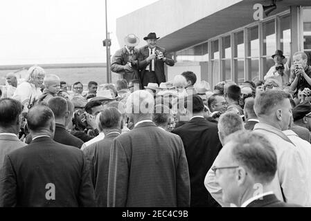 Voyage aux États de l'Ouest : Pierre, Dakota du Sud (barrage d'Oahe), 10:25. Le président John F. Kennedy (au centre-droit, la plupart caché dans la foule) accueille les visiteurs à son arrivée à l'aéroport municipal de Pierre à Pierre, Dakota du Sud; le président Kennedy s'est rendu au Dakota du Sud pour assister à l'inauguration du barrage et du réservoir d'Oahe. Banque D'Images