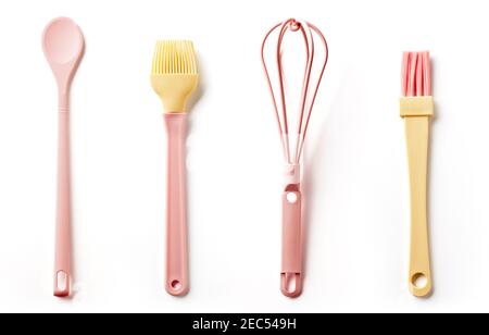 Ensemble d'ustensiles de cuisine en silicone rose et jaune isolés sur fond blanc ; vue du dessus ; cuillère, fouet, pinceau à pâtisserie Banque D'Images