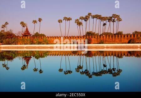 Ancien mur de brique brune du palais avec réflexion dans le canal entourant le palais Mandalay situé à Mandalay, Birmanie (Myanmar) au lever du soleil Banque D'Images