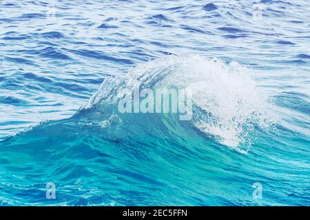 Vague bleue turquoise sur l'eau de mer ondulée. Photo de gros plan sur l'eau de mer. Tourbillon de la vague de mer. Surf en bord de mer. Nettoyez les éclaboussures du chariot de magasinier. Concept de vacances en bord de mer. M Banque D'Images