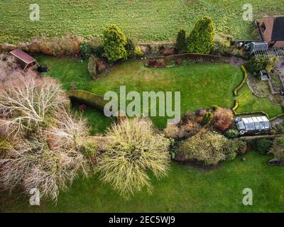 Vue sur un jardin à l'arrière d'une maison de campagne anglaise, montrant des enfants jouant au football par une journée ensoleillée. Banque D'Images