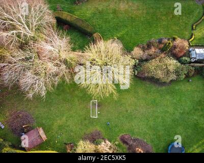 Vue sur un jardin à l'arrière d'une maison de campagne anglaise, montrant des enfants jouant au football par une journée ensoleillée. Banque D'Images