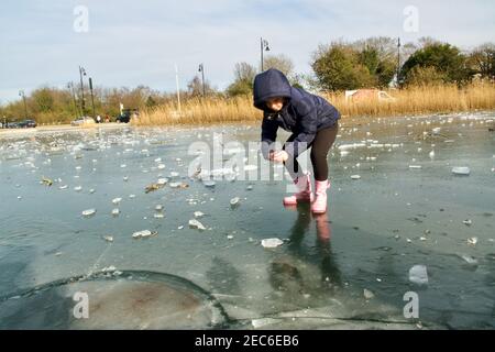 Une jeune fille marchant sur la glace mince d'un étang gelé. Whitestone Pond, sur Hampstead Heath, est le point le plus élevé de Londres à 135 mètres au-dessus du bassin de Londres. Météo Royaume-Uni. Hampstead, Londres, Royaume-Uni 13 février 2021. Banque D'Images