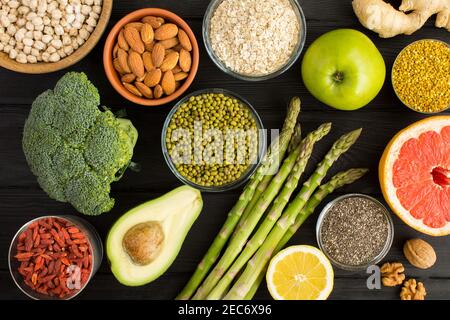 Superfood ou végétarien concept alimentaire.légumes, fruits, légumineuses, noix et pollen d'abeille sur fond de bois noir.vue du dessus. Banque D'Images