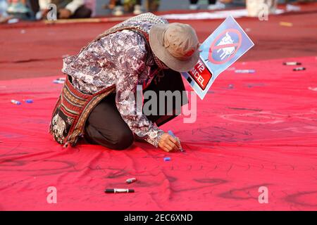 Bangkok, Thaïlande. 13 février 2021. Un manifestant pro-démocratie écrit des mots sur un tissu rouge lors d'un rassemblement exigeant la démission du Premier ministre et des réformes sur la monarchie, à Bangkok. Crédit : SOPA Images Limited/Alamy Live News Banque D'Images