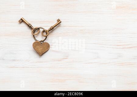Les anciennes touches de couleur bronze ont été accroché au coeur sur fond en bois peint blanc vintage. Vue de dessus. Pose à plat. Copier l'espace. Concept d'amour ou de maison douce. Banque D'Images
