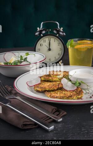 Crêpes de pommes de terre sur une assiette blanche. Salade de légumes frais et boisson à la limonade. Déjeuner à 12:00 Banque D'Images