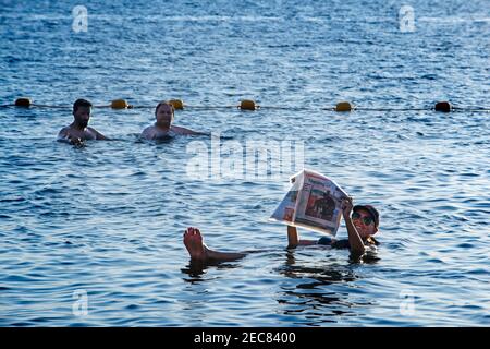 Jeune femme flottant et la lecture d'un magazine dans la mer Morte, Jordanie Banque D'Images