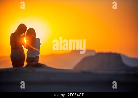 Deux filles touristes regardant sur les sables rouges du désert de Wadi Rum au coucher du soleil, Jordanie Banque D'Images