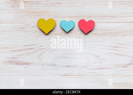 Scène de la Saint-Valentin avec coeurs en bois colorés sur fond blanc peint en bois vintage. Vue de dessus, plat, espace vide pour le texte Banque D'Images