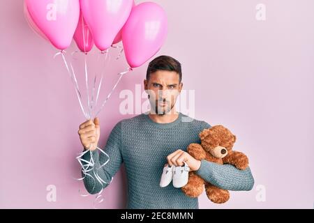 Beau homme avec la barbe s'attendant à une petite fille tenant des ballons, des chaussures et l'ours en peluche sceptique et nerveux, frognant bouleversé à cause du problème. Négatif Banque D'Images