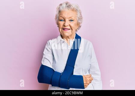 Femme sénior aux cheveux gris portant le bras sur le harnais ayant l'air positif et se tenir debout et sourire avec un sourire confiant montrant les dents Banque D'Images