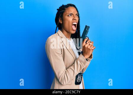 La police afro-américaine qui tient le fusil en colère et en colère hurle frustré et furieux, criant avec colère. Rage et concept agressif. Banque D'Images