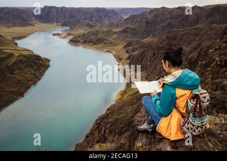 Fille s'inspire de la nature paysage de printemps. Peinture à l'extérieur. Peinture plein air. Une fille est assise sur un rocher au bord de la rivière. Rivière SG. Kazakhstan. Banque D'Images