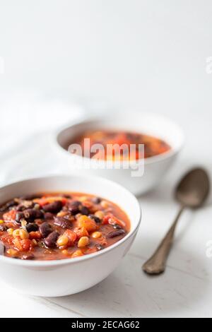 Préparation de haricots au Chili aux légumes avec haricots rouges, tomates, maïs soufflé, poivrons rouges et jaunes sur plat Banque D'Images